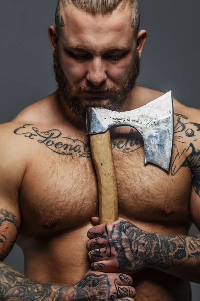 Grande homem brutal com tatuagens e barba segurando machado — Fotografia de Stock