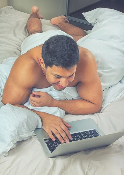 Joven usando portátil a la hora de acostarse — Foto de Stock