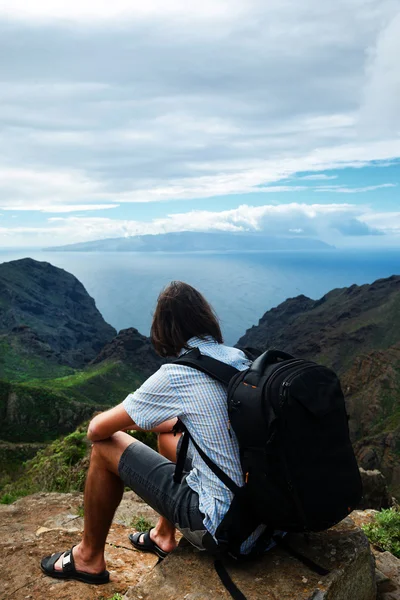 Чоловік сидить на пагорбі над горами і морем — стокове фото