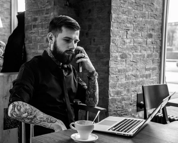 Tattoe man met baard en laptop. — Stockfoto