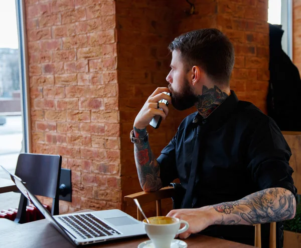 Tattoe muž s plnovousem a laptop. — Stock fotografie