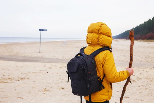 黄色のジャケットの男性が浜辺に立つ. — ストック写真