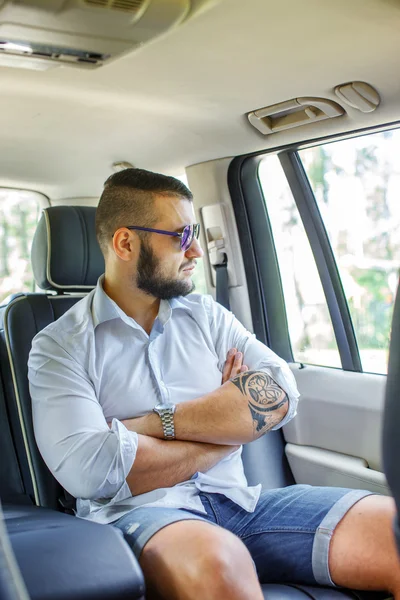 Feliz ingenio masculino beart y tattoe en un coche . —  Fotos de Stock