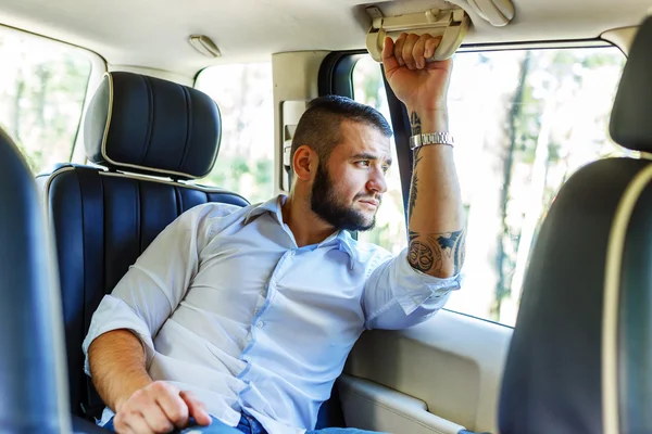 Happy male wit beart and tattoe in a car. — Stock Photo, Image