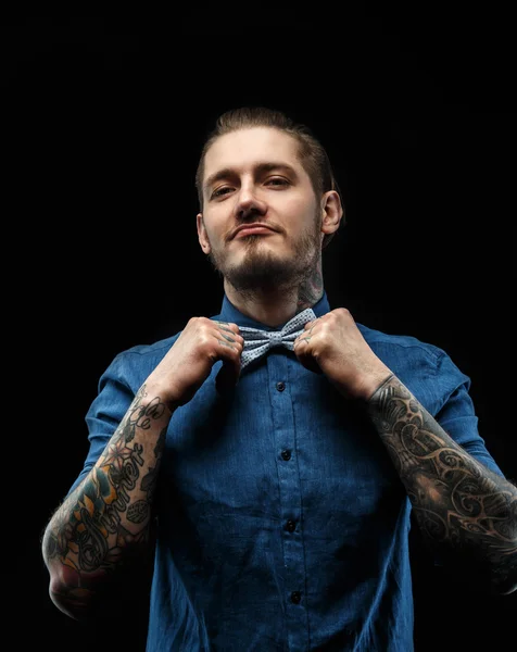 Man in blue shirt with tattooes.