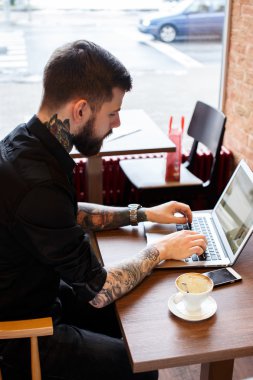 Bir kafede dizüstü bilgisayar ile çalışan adam