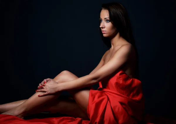 Kvinna i röd klänning poserar i studio. — Stockfoto