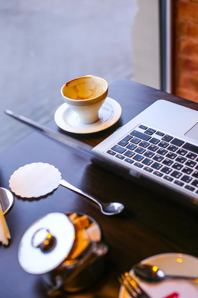 Laptop e xícara de café em uma mesa — Fotografia de Stock