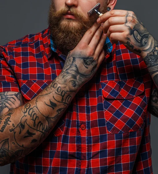 Brutal hombre tatuado afeitándose la barba — Foto de Stock