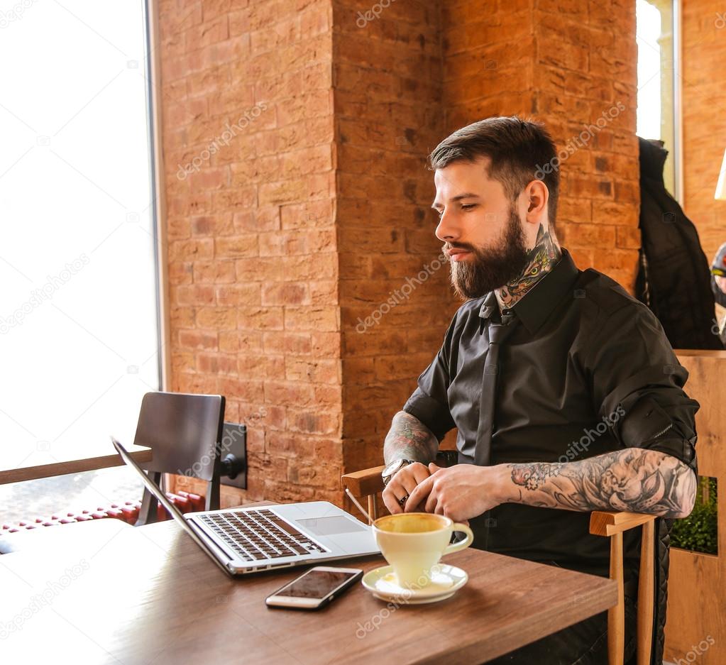 Tattoed man sitting in a cafe