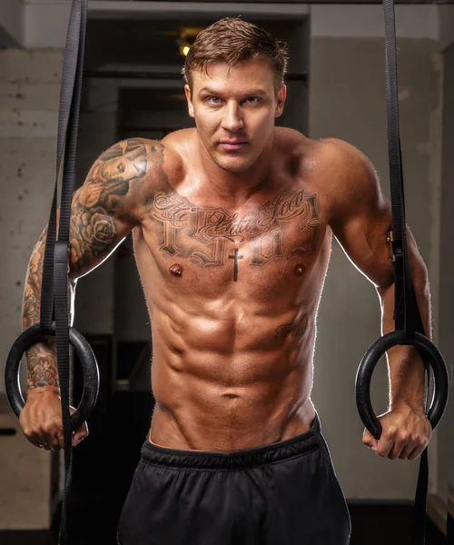 Musculoso chico con tatuajes en un gimnasio — Foto de Stock