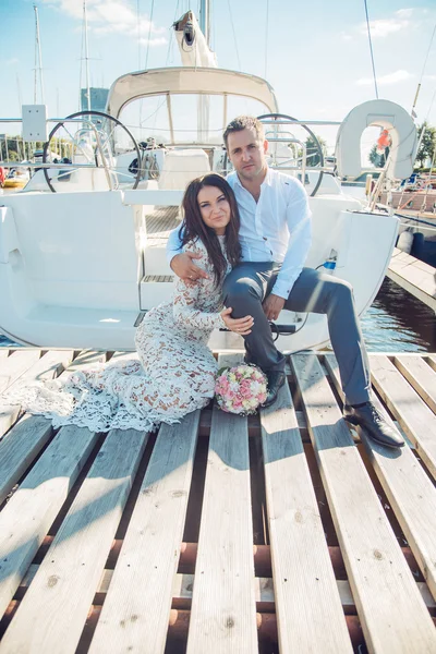 Beautiful couple sitting near yachts — Stock Photo, Image