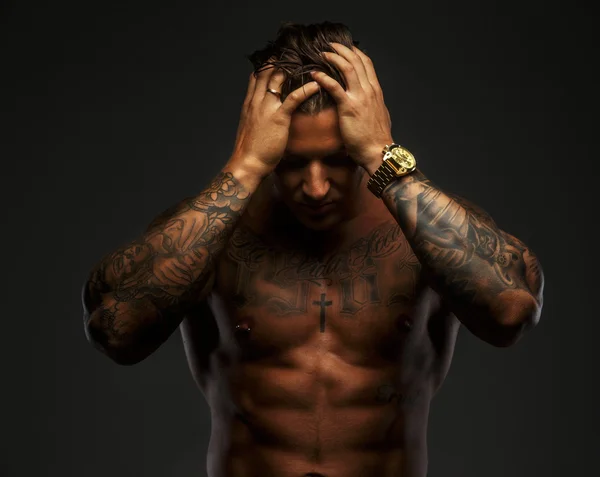 Homem muscular com tatuagens em sombras profundas — Fotografia de Stock