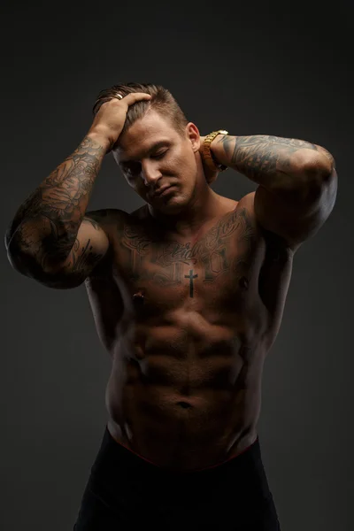 Hombre musculoso con tatuajes en sombras profundas — Foto de Stock