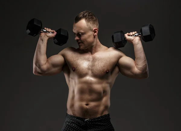 Потрясающий мускулистый парень с гантелями — стоковое фото