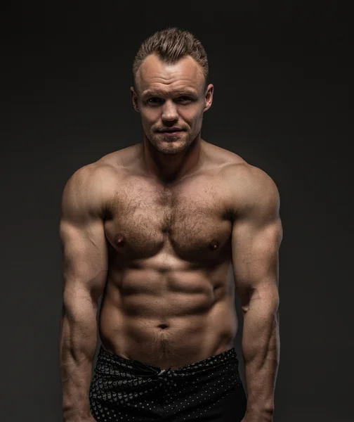 Muskulöser Mann posiert im Studio auf grauem Hintergrund — Stockfoto