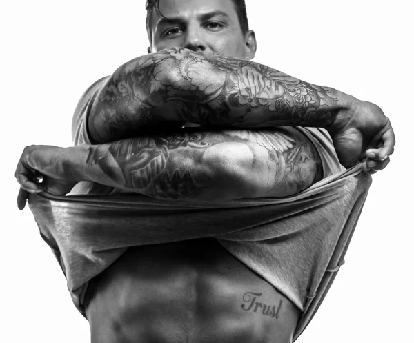 Man with tattooes undressing on white background — Stock Photo, Image