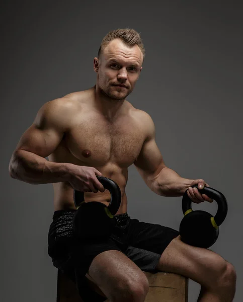 Muscular cara em shorts pretos sentado no pódio — Fotografia de Stock