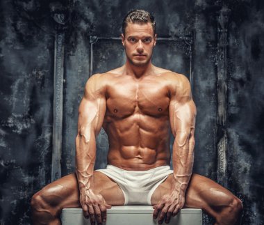  kaslı adam beyaz podyuma oturan.