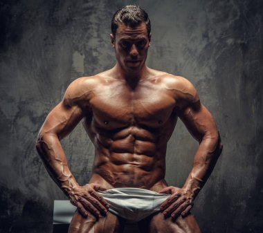  kaslı adam beyaz podyuma oturan.