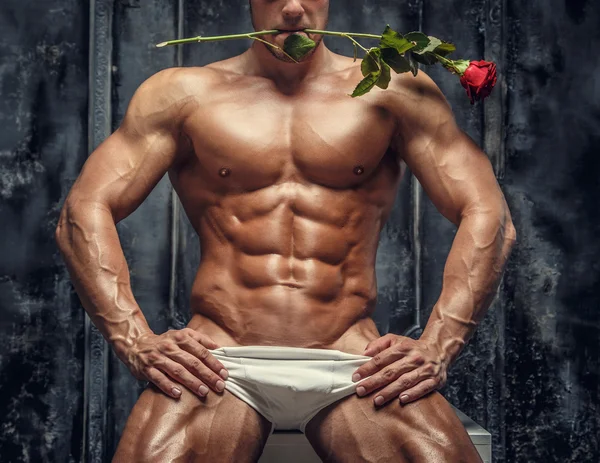 Félmeztelen izmos srác tartja a piros rózsa — Stock Fotó