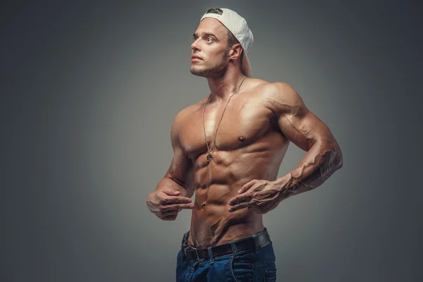 Guy en casquette blanche montrant son corps musclé . — Photo