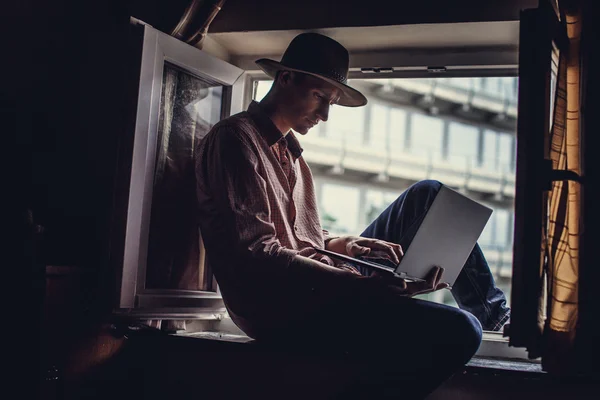 Un tipo con sombrero grande sentado en la ventana — Foto de Stock