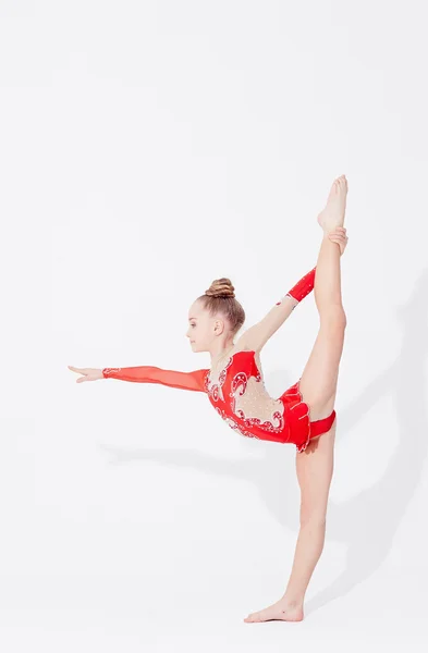Дівчина-підліток в червоній сукні виконує гімнастичні вправи — стокове фото