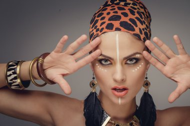 Jeune femme avec exotique composent holdin mains près de son visage. Isolé sur fond gris 