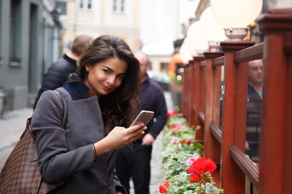 Sonriente chica morena con smartphone — Foto de Stock