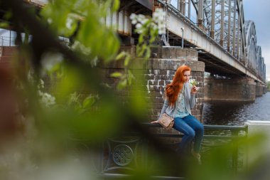 Kızıl saçlı casual kız büyük nehir kenarında poz.