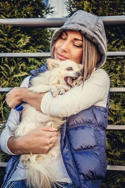 Casual woman holding small white dog. — Stock Photo, Image