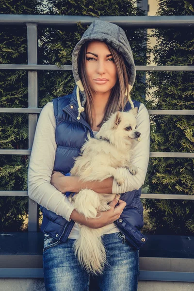 Casual woman holding small white dog. — Stock Photo, Image