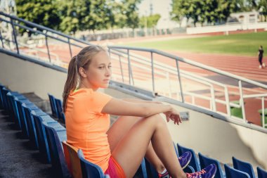 Plastik koltukta oturan sarışın kadın.