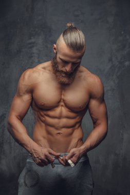Sakallı gömleksiz vücut geliştirmeci.