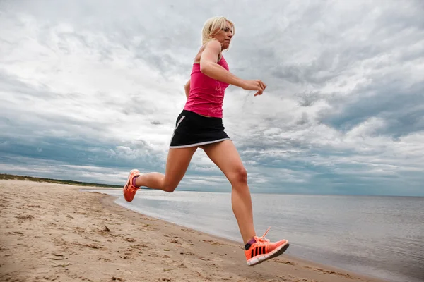 Sportig blond kvinna kör på stranden — Stockfoto