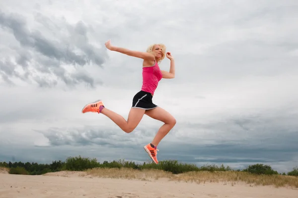 Jumping blond woman in summer sportswear. — Stock Photo, Image