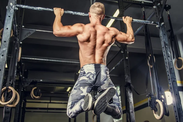 Shirtless man pulling up on horizontal bar. — Stock Photo, Image