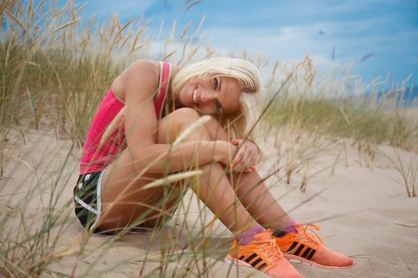 Hermosa mujer rubia sentada en la arena . —  Fotos de Stock