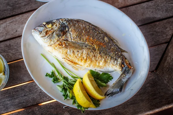 Comida de peixe em prato branco com limão . — Fotografia de Stock