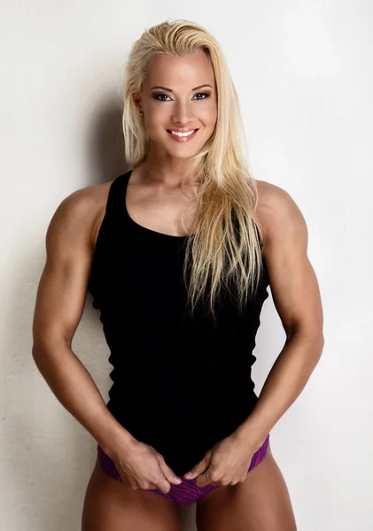 Lächelnde blonde Frau in schwarzer Sportbekleidung. — Stockfoto
