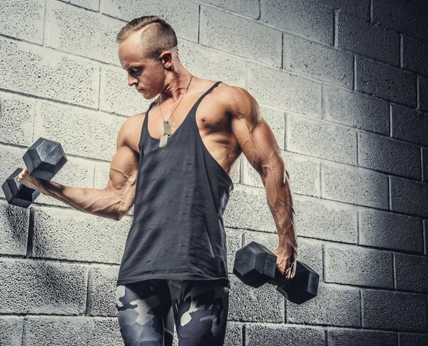 Jonge man doen oefeningen met dumbells. — Stockfoto