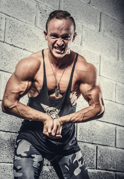 Enojado muscular chico posando sobre la pared — Foto de Stock