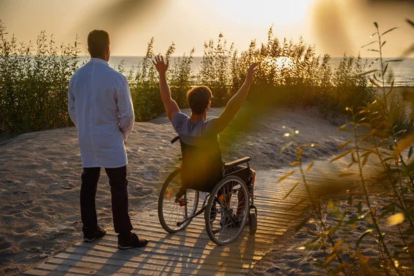 Mladý muž ve vozíku a jeho lékař. — Stock fotografie