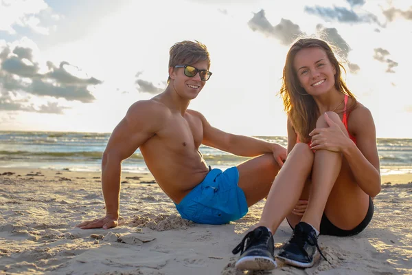 Sporty homem e mulher relaxante na praia . — Fotografia de Stock