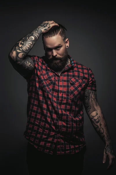 Man with beard and tattoo holding his head. — Stock Photo, Image