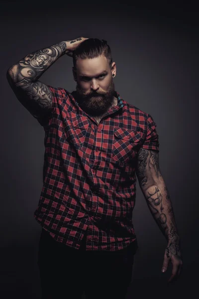 Man with beard and tattoo holding his head. — Stock Photo, Image