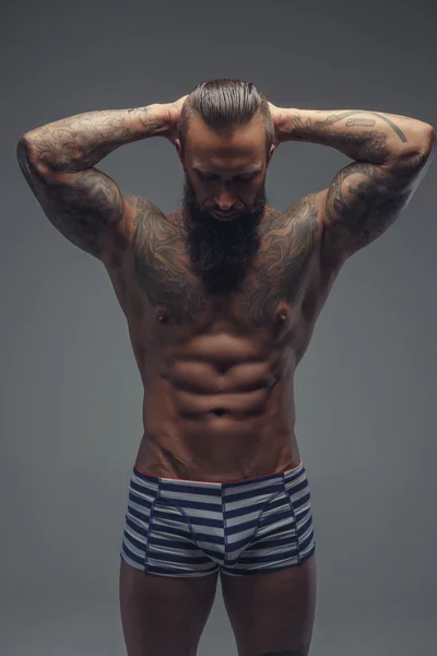 Tattooed bearded man in stripes panties. — Stock Photo, Image