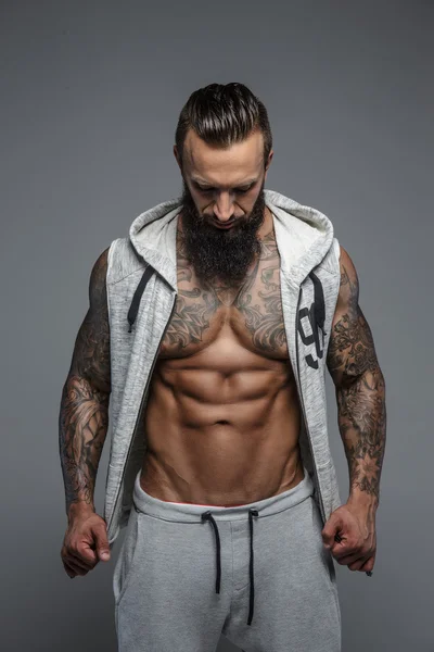 Brutal hombre tatuado con capucha gris . — Foto de Stock