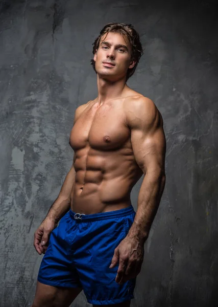 Awesome shirtless bodybuilder in blauwe korte broek. — Stockfoto